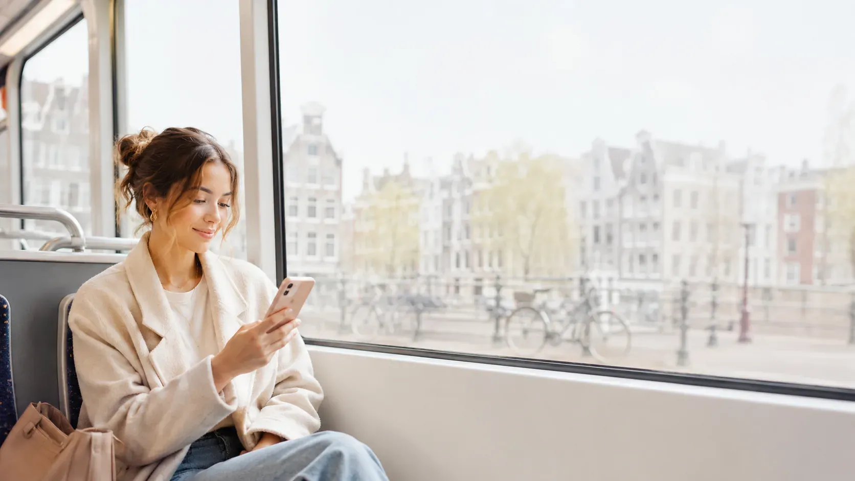 A young expat on her phone reviewing a Dutch tax letter on an Amsterdam tram.